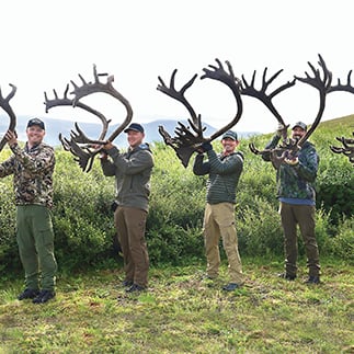 Experienced hunter mentoring family in snowy wilderness during mule deer and elk hunt, evoking stages of hunting evolution