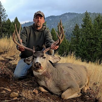 Father and son hunters posing with massive 30-inch mule deer buck in Oregon public land during rut season harvest