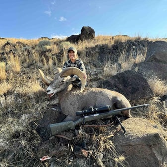 Hunter Tori Roberts with her trophy bighorn sheep ram Ol' Wonky on Oregon mountain after one-shot harvest in challenging weather