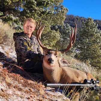Hunter Jackson Jessop with heavy 4x5 mule deer buck in snowy Idaho high country after solo rifle harvest amid rocky spines