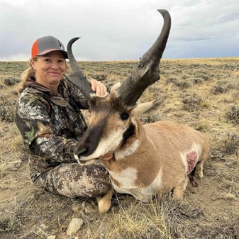 Hunter Myra Smith with asymmetrical one-horned pronghorn antelope trophy in Wyoming plains after 275-yard rifle shot with guides