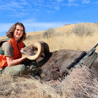 Teen hunter Rhett Janosky with solid California bighorn sheep ram in rugged Washington Chelan Butte terrain after one-shot harvest