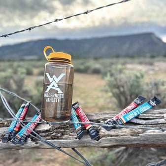 Wilderness Athlete Hydrate & Recover packets alongside Energy & Focus for hunter's Superman blend in rugged backcountry terrain